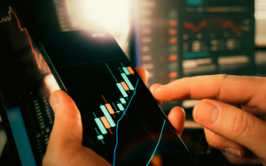A professional looking at a computer screen showing portfolio charts alongside a physical financial plan.