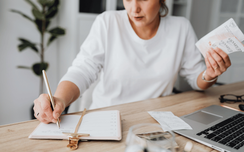 woman making notes at her desk trying to decide if she can self-fund her long-term care