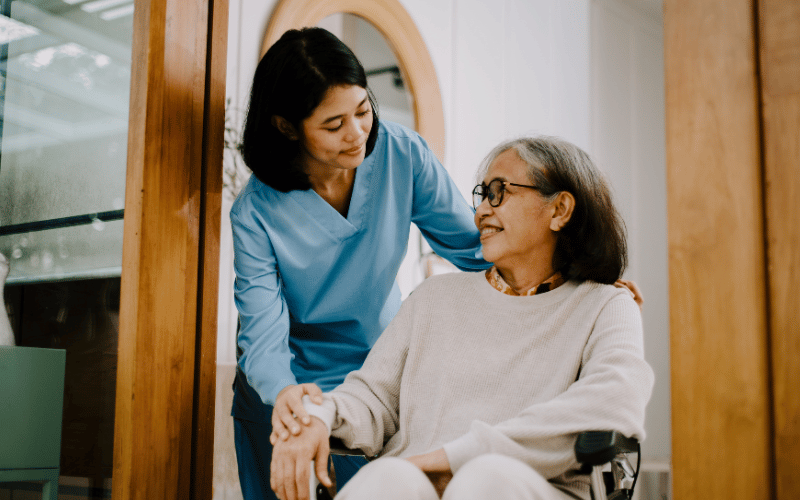elderly lady in a wheelchair being assisted by a health care worker